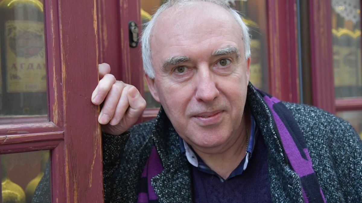 Ростислав Прокоп'юк, голова Українського інституту в Празі, психолог, художник і письменник, у шарфі біля дерев'яних дверей