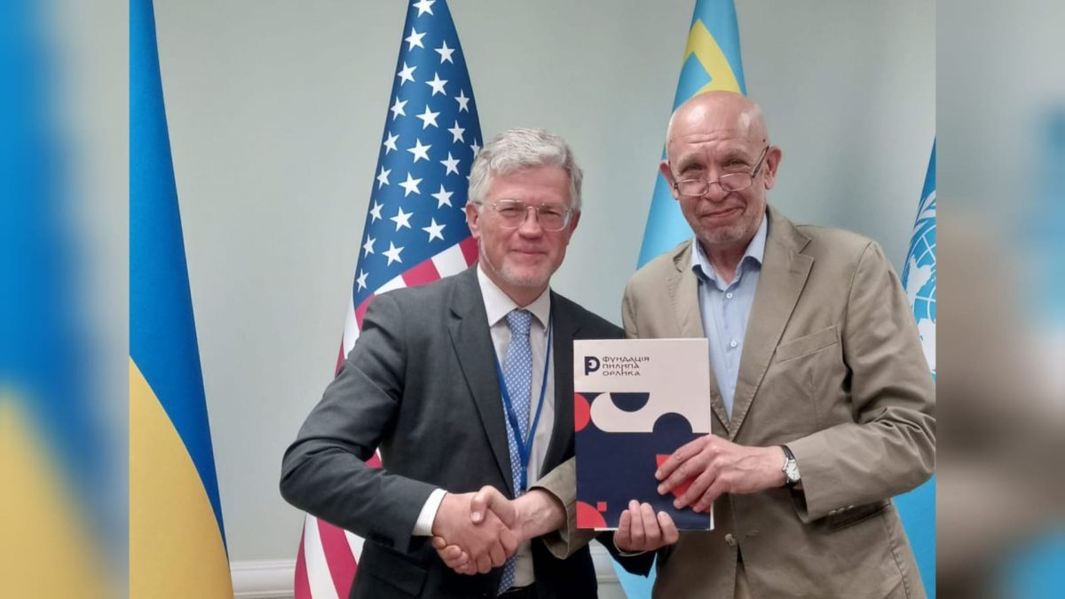 Постійний представник України при ООН Андрій Мельник та посол Ігор Харченко тиснуть руку у Нью-Йорку на фоні прапорів України, США та ООН
