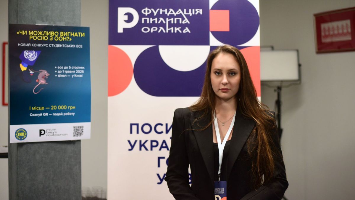 Катерина Опанасенко на заході Фундації Пилипа Орлика на тлі банеру конкурсу студентських есе «Чи можливо вигнати Росію з ООН?»