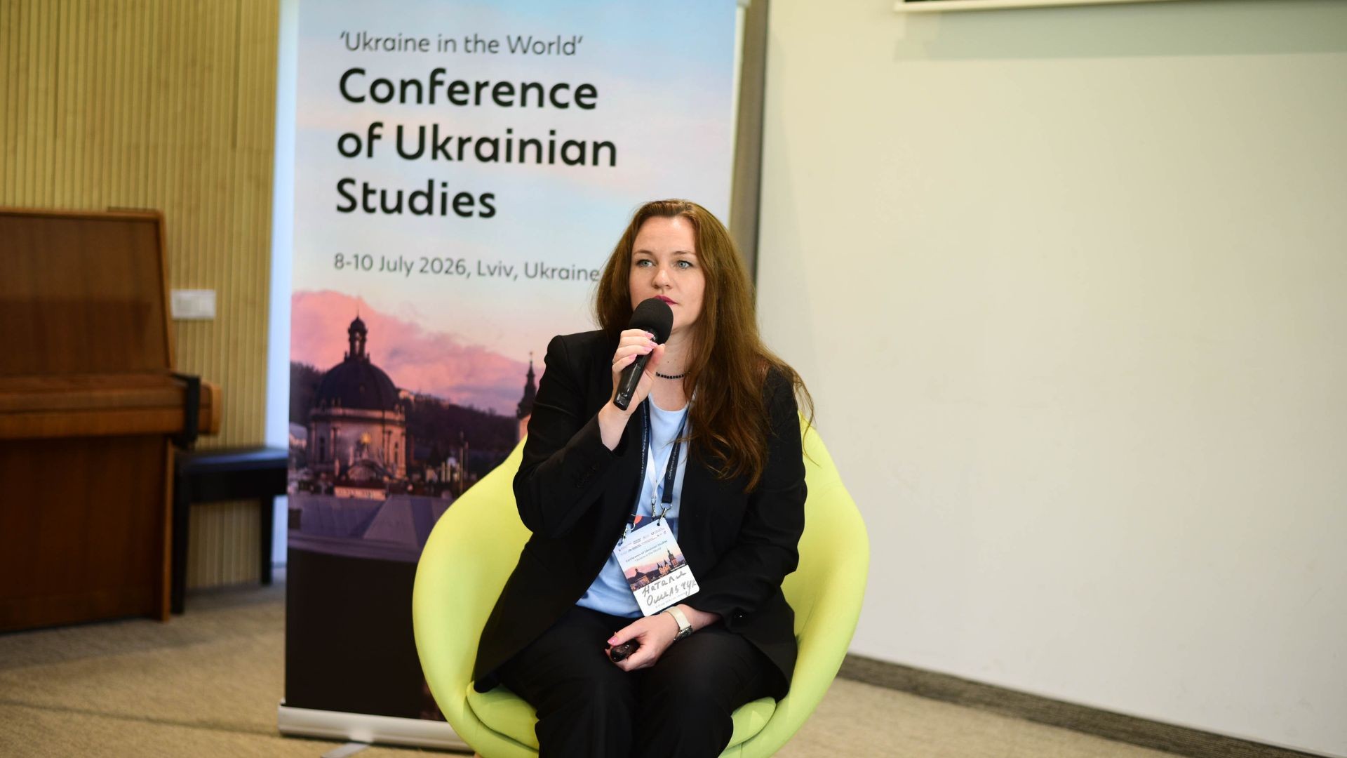 Наталя Омельчук виступає з мікрофоном на тлі банера конференції «Україна у світі» у Львові, 8–10 липня 2026 року