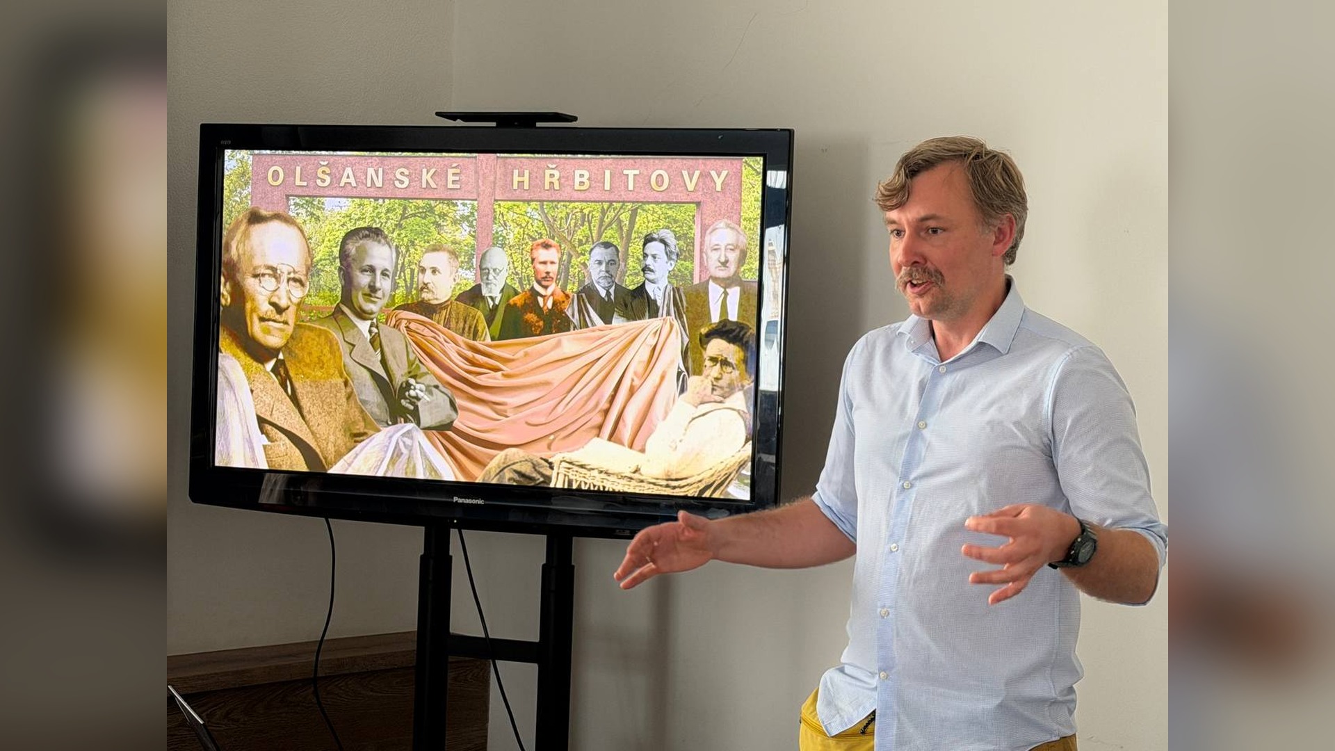 Historian Volodymyr Poltorak gives a lecture against a screen showing an image of the Olšany Cemetery in Prague