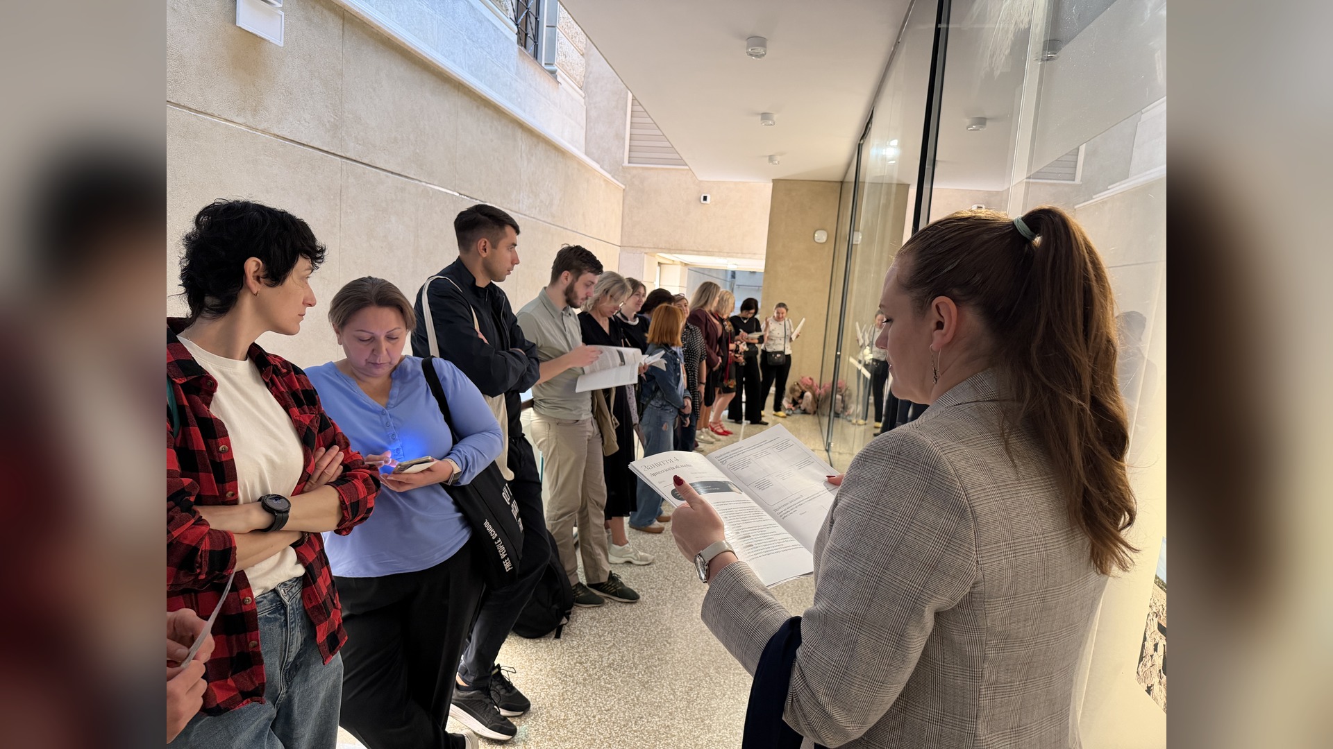 Participants stand in a museum corridor, holding and looking through a practical workbook during the session
