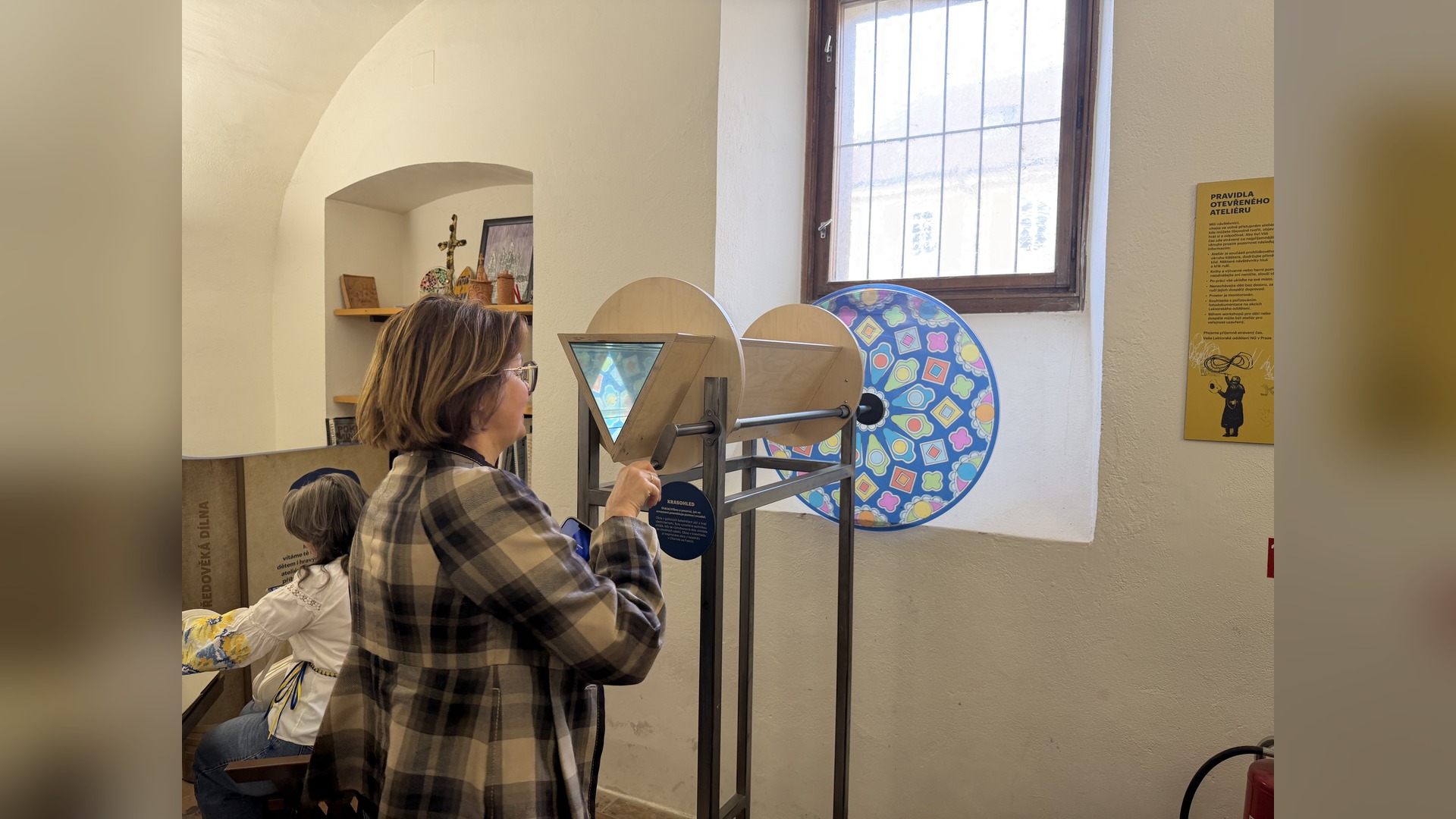 A program participant turns the handle of an interactive landscape exhibit in an open museum studio