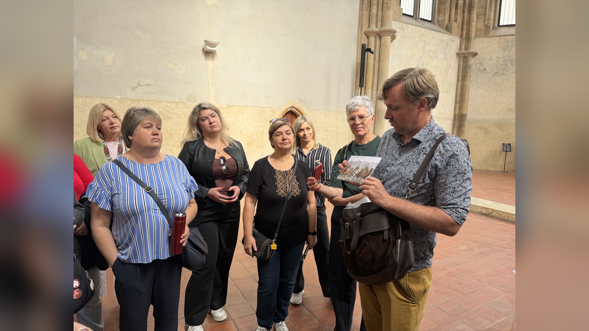 Historian Volodymyr Poltorak shows program participants historical postcards in a Gothic hall during the tour