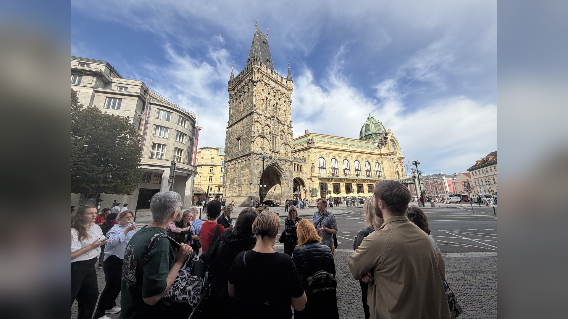 Participants of the program listen to a guide on the square in front of the Powder Gate in Prague during a themed walk