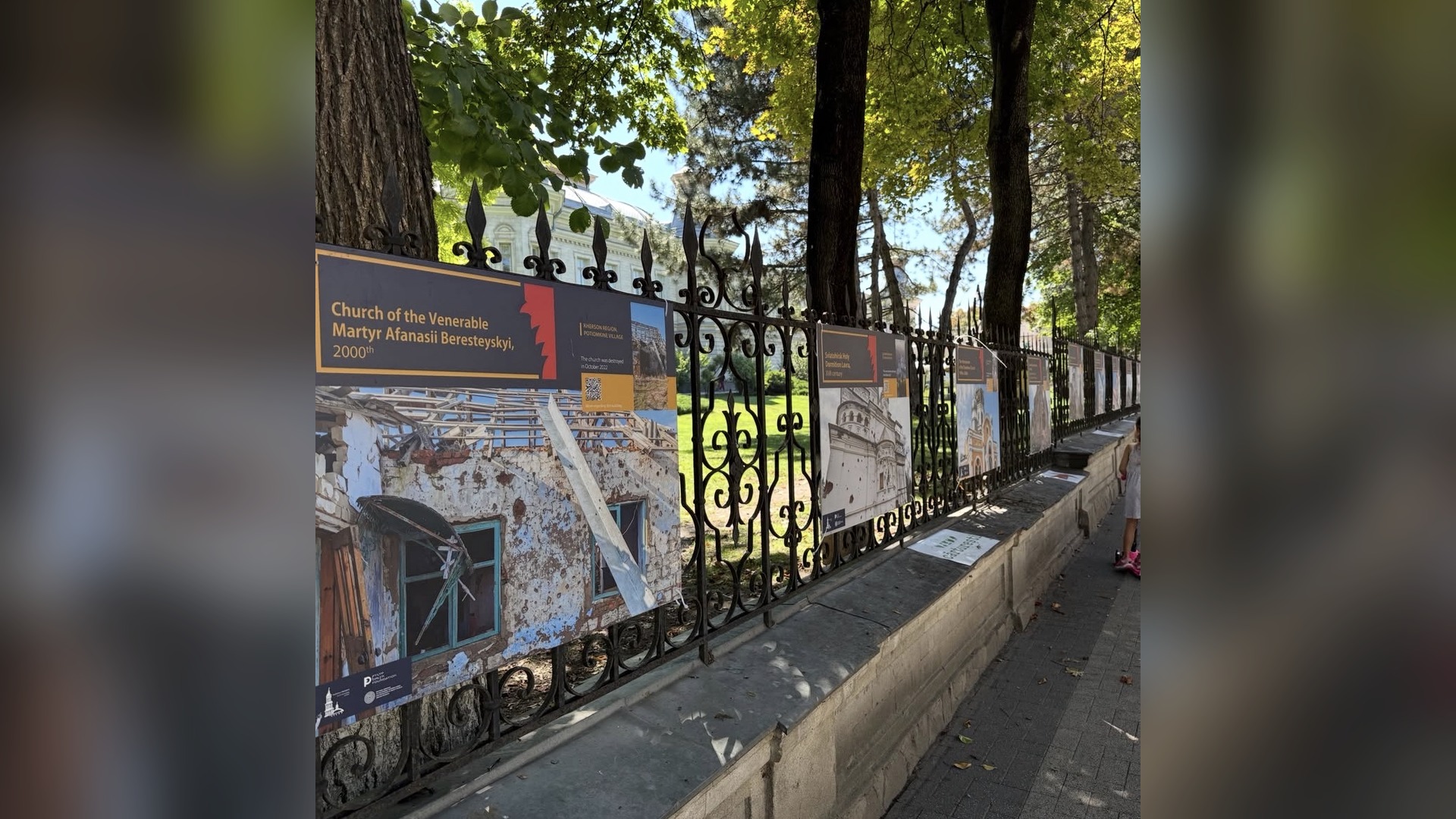Стенди виставки про зруйновані російською агресією українські храми на кованій огорожі парку в Кишиневі