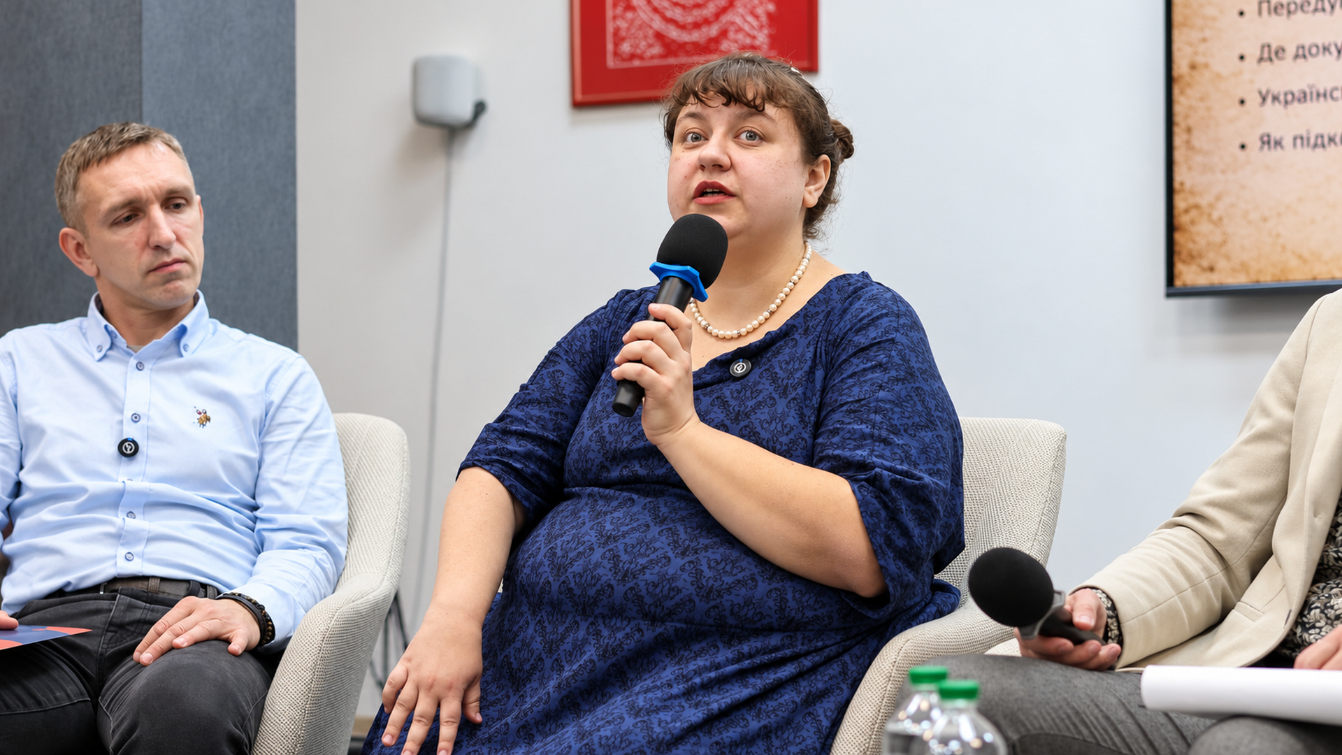 Inna Kovalyshena speaking into a microphone during the panel discussion, with Oleksii Yushchenko seated next to her