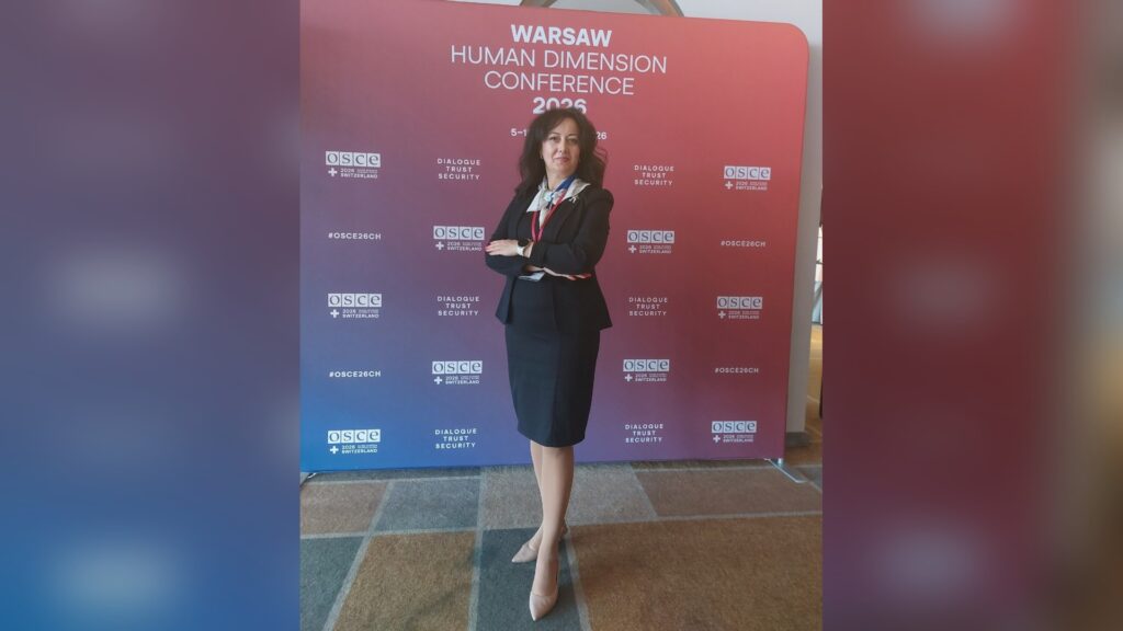 Радниця Фундації Пилипа Орлика Юлія Мізюкіна на тлі банера Warsaw Human Dimension Conference 2026 ОБСЄ