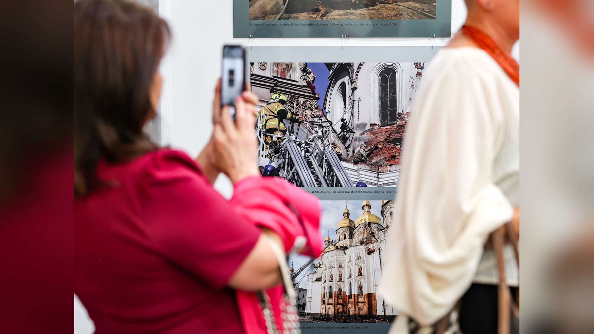 Відвідувачка фотографує на смартфон знімки пошкодженого Успенського собору Києво-Печерської лаври на виставці в Чикаго