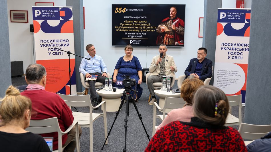 Учасники панельної дискусії «Ефект метелика Орликової конституції» сидять у кріслах перед глядачами, на екрані — портрет гетьмана