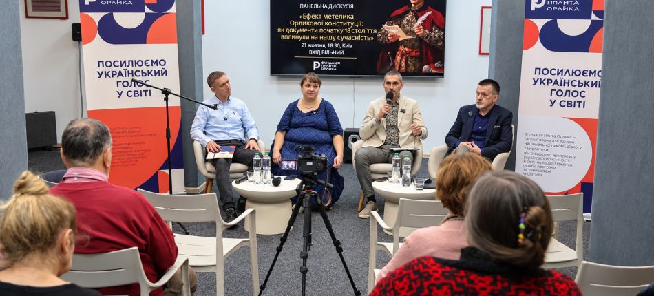 Учасники панельної дискусії «Ефект метелика Орликової конституції» сидять у кріслах перед глядачами, на екрані — портрет гетьмана