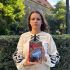 Ксенія Дворнікова тримає книгу «Вижити в Гостомелі: 21 історія з міста-героя» на вулиці в Празі