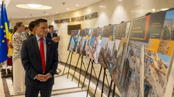 Відвідувач розглядає стенди фотовиставки про зруйновані українські храми в холі Парламенту Республіки Молдова