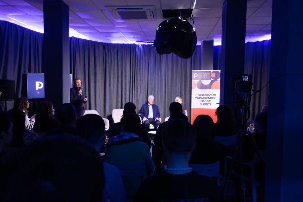 Загальний вигляд зали публічної дискусії Rethinking Russia — ведуча з мікрофоном і спікери на сцені