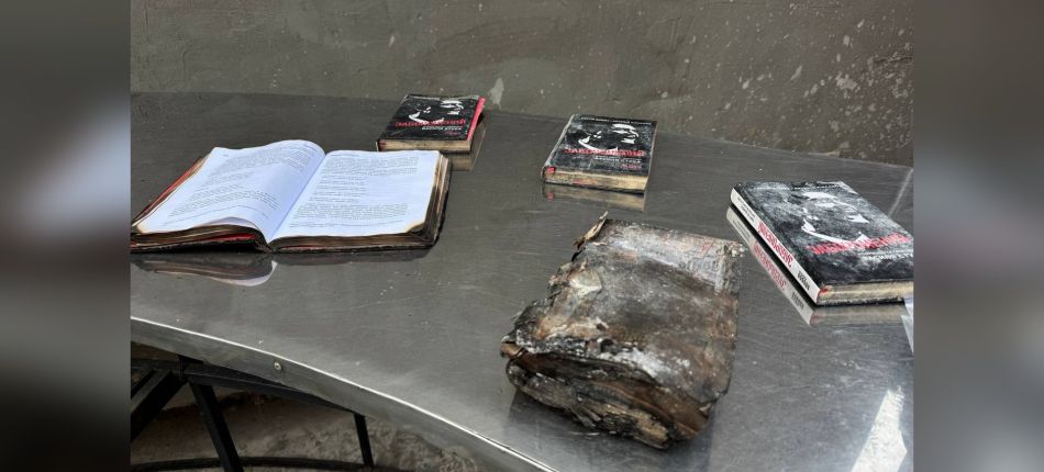 Обгорілі та пошкоджені книги на металевому столі після російського удару по видавництву