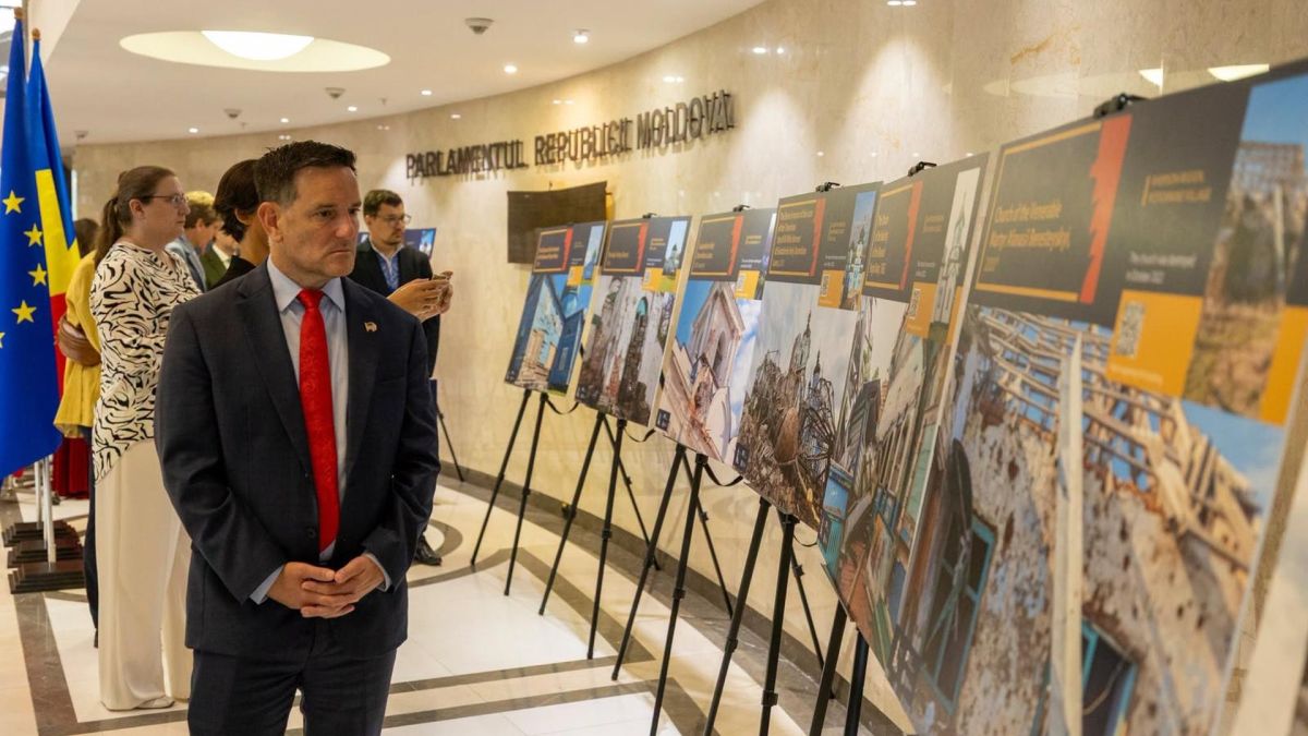 Відвідувач розглядає стенди фотовиставки про зруйновані українські храми в холі Парламенту Республіки Молдова
